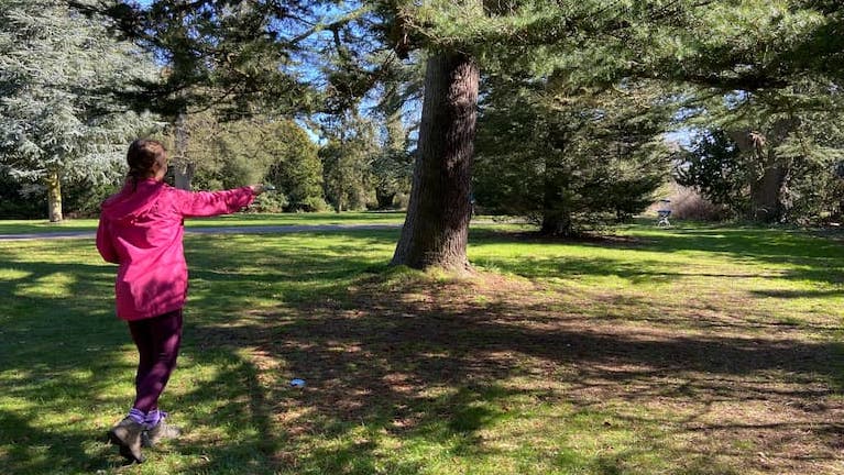 Female disc golf player prparing to throw around a tree to the basket